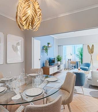 Sala de jantar aberta para a sala de estar com pavimento de madeira, paredes pintadas com tinta bege e molduras brancas e mobiliário 